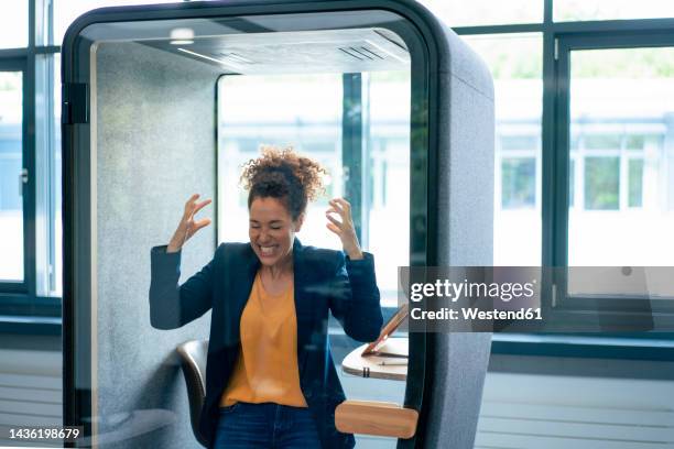 frustrated businesswoman clenching teeth inside soundproof cabin at workplace - cerrando os dentes - fotografias e filmes do acervo