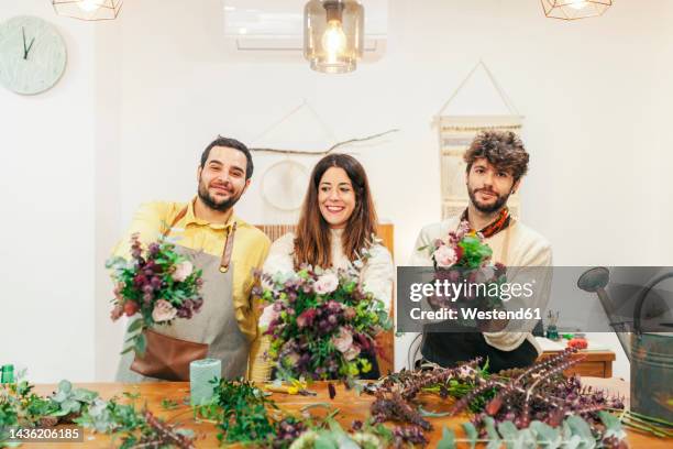 smiling florists holding bouquets standing at floral shop - arreglo floral fotografías e imágenes de stock