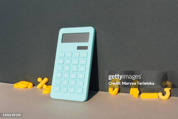 blue calculator and math symbols on a universal gray background. gray background. blue calculator. math symbols. - financial literacy stock pictures, royalty-free photos & images