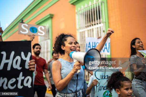 mid adult woman leading a protest using a megaphone - anti globalization stock pictures, royalty-free photos & images