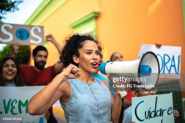 mid adult woman leading a protest using a megaphone - fist raised stock pictures, royalty-free photos & images