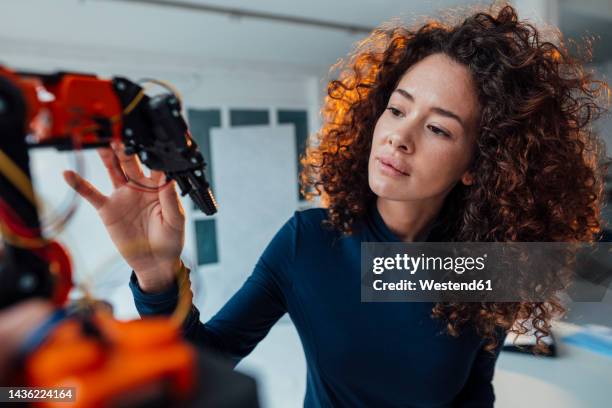 engineer examining robotic arm in office - female development stockfoto's en -beelden