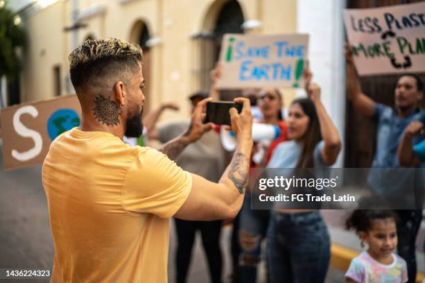mittlerer erwachsener mann, der einen protest auf einem mobiltelefon im freien aufzeichnet - childrens justice campaign event stock-fotos und bilder