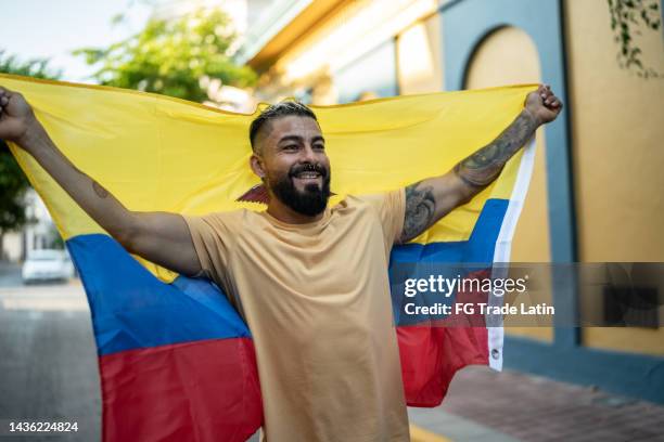 mid adult man holding ecuadorian flag in the street - venezuela flag stock pictures, royalty-free photos & images