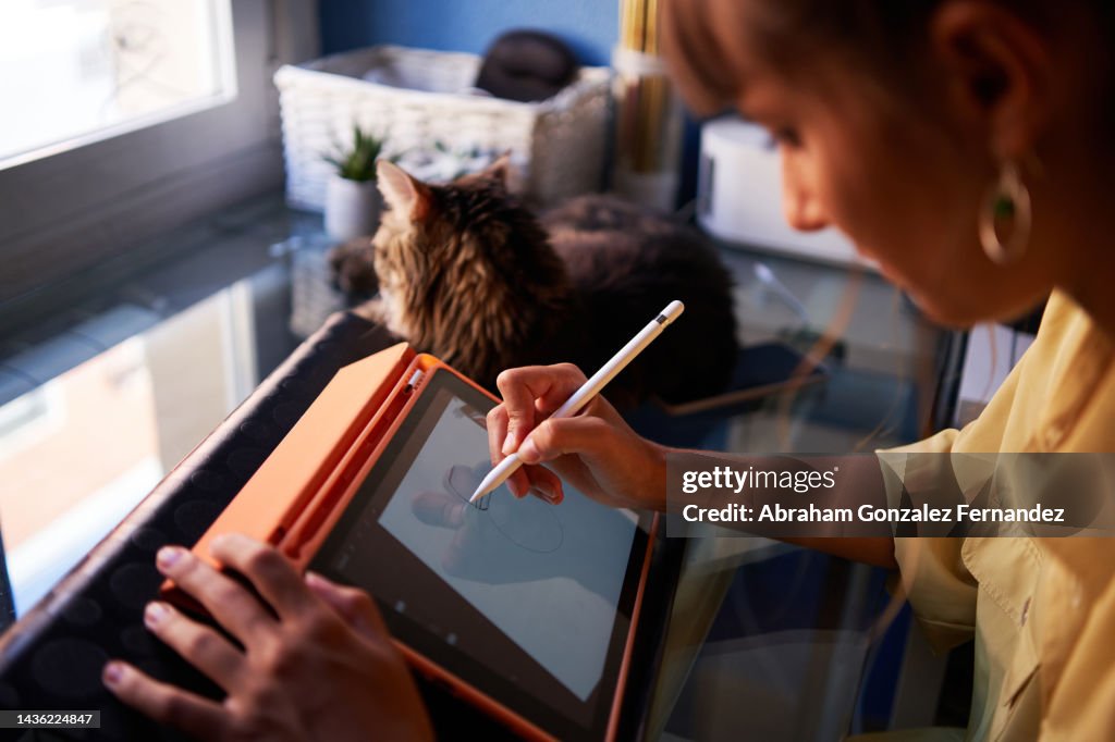 A graphic designer making a drawing on her digital tablet as a work at home