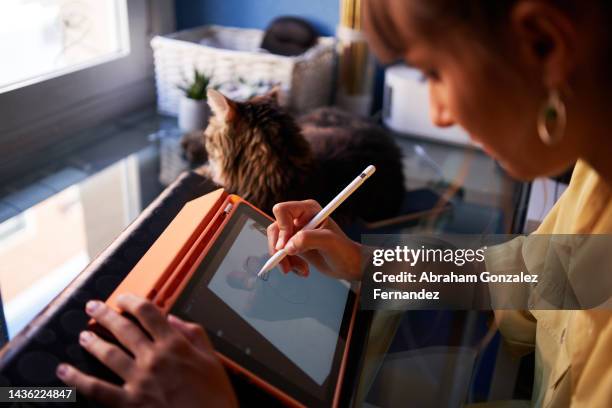 a graphic designer making a drawing on her digital tablet as a work at home - designer stockfoto's en -beelden