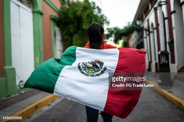 mid adult woman walking with a mexican flag in the street - mexican artists celebrate el grito the cry of independence stockfoto's en -beelden