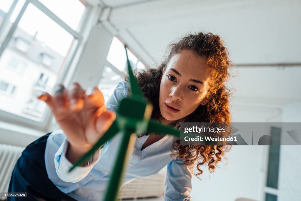 Engineer with curly hair analyzing wind turbine model in office