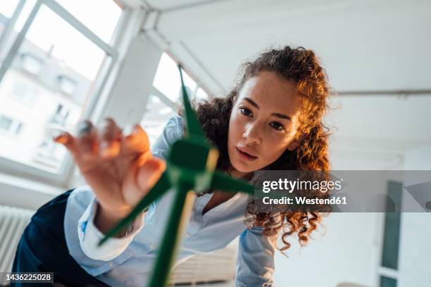 engineer with curly hair analyzing wind turbine model in office - low angle view room stock pictures, royalty-free photos & images