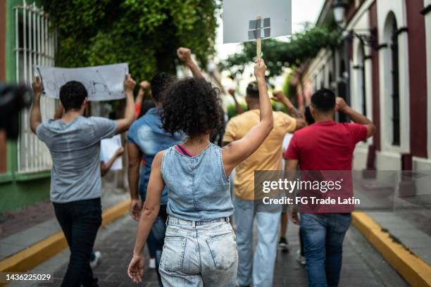protesters walking while holding signs during on a demonstration outdoors - politieke bijeenkomst stockfoto's en -beelden