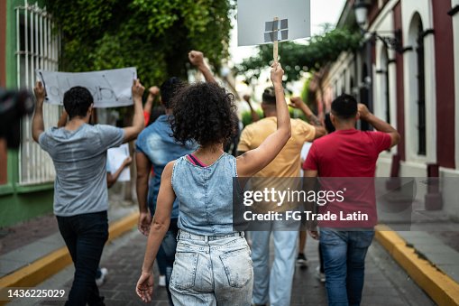 Protesters walking while holding signs during on a demonstration outdoors