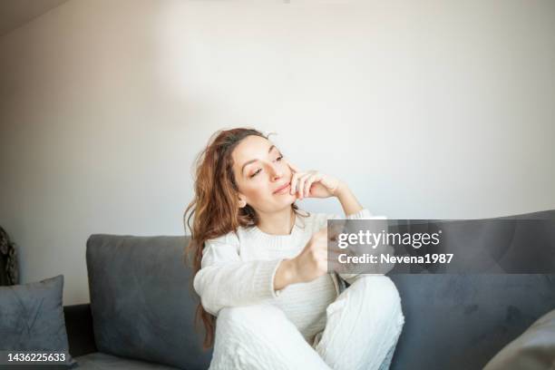 woman enjoying a cup of coffee in winter at home - destiny stockfoto's en -beelden