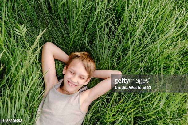 happy boy with eyes closed lying down on grass - child lying down stock pictures, royalty-free photos & images