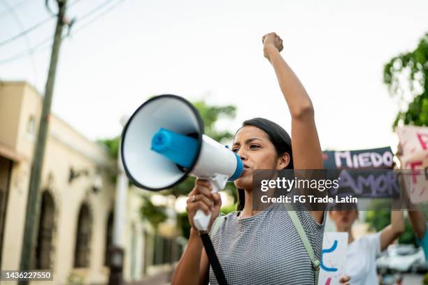 joven manifestante sosteniendo un cartel en una protesta al aire libre - megaphone fotografías e imágenes de stock