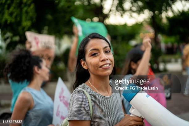 retrato de una mujer joven con un megáfono en una protesta al aire libre- - protest photos fotografías e imágenes de stock