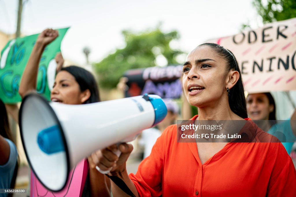 Mulher adulta média liderando uma demonstração usando um megafone ao ar livre