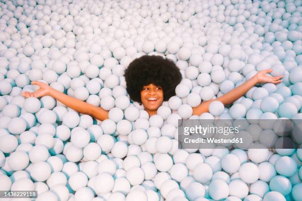 young woman with arms outstretched in ball pit - woman effortless stock pictures, royalty-free photos & images