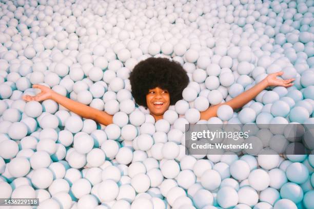 young woman with arms outstretched in ball pit - smooth stock pictures, royalty-free photos & images
