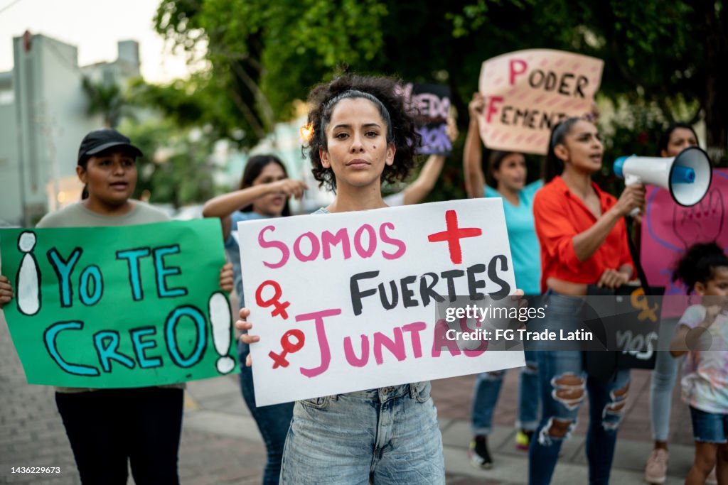 Portrait of mid adult protester woman holding a sign on a demonstration outdoors