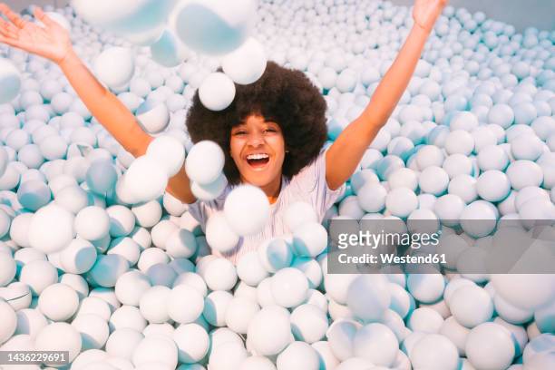 playful young woman playing in ball pool - adult ball pit stock pictures, royalty-free photos & images