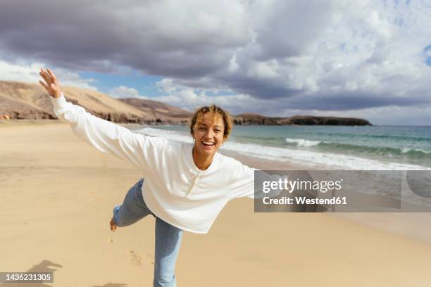 happy woman with arms outstretched enjoying at beach on sunny day - 飛行機のまね ストックフォトと画像