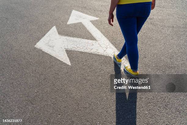 woman standing on arrow symbol - low section of woman standing in front of arrow sign on road stock pictures, royalty-free photos & images