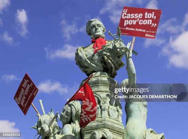Placards reading anti-Sarkoy slogans and a flag of French Front de Gauche leftist party are seen on a statue during a march as part of the annual May...