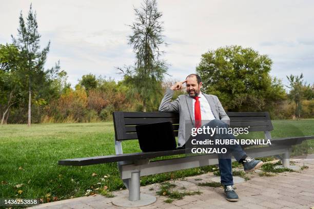 businessman using laptop while working on park bench. working concept. - gonzalo caballero fotografías e imágenes de stock