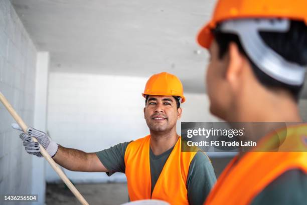 young painters / construction workers painting a wall and talking indoors - painter in overhauls bildbanksfoton och bilder