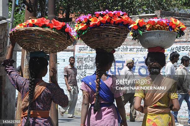 Indian vendors carry baskets of hand made artificial flowers in Amritsar on May 1, 2012. Countries across the world celebrate May 1, as International...