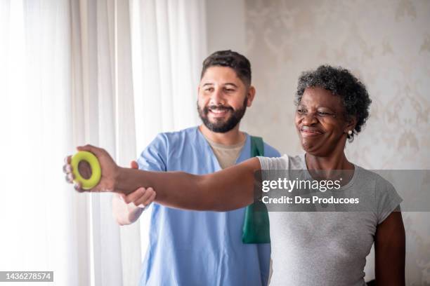 mujer madura haciendo fisioterapia junto con un enfermero - fisioterapia fotografías e imágenes de stock