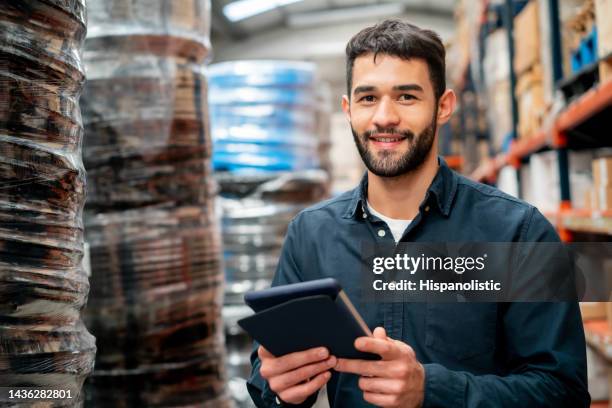 homme joyeux travaillant dans un entrepôt tenant une tablette tout en souriant face à la caméra - magasinier photos et images de collection