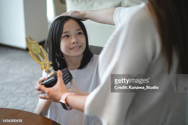 asiatische mutter lobt ihre tochter für den gewinn eines schulwettbewerbs - teen awards stock-fotos und bilder