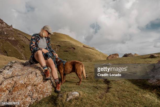 a female hiker resting in scotland with her dogs - old man of storr stock pictures, royalty-free photos & images