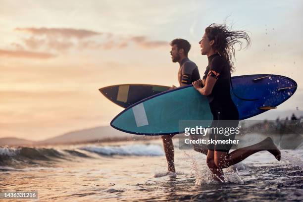 rushing to surfing at sunset! - prancha de surf imagens e fotografias de stock