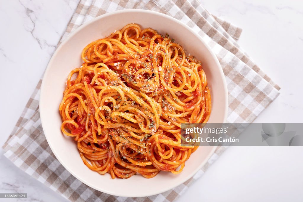 Spaghetti with tomato sauce on white background.