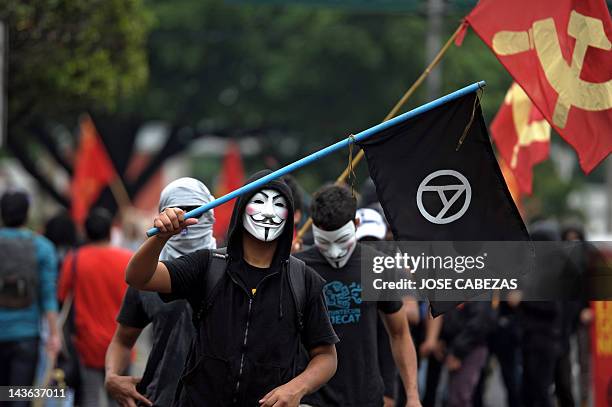 Man wering a Guy Fawkes mask flutters an Anarchy flag as he takes part in a demo in the framework of Labour Day in San Salvador, El Salvador on May...