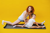 Hyped mom and little daughter exercising together, doing splits