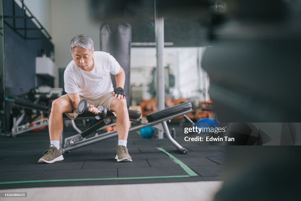 Asian Chinese Senior Man workout with dumbbell in gym