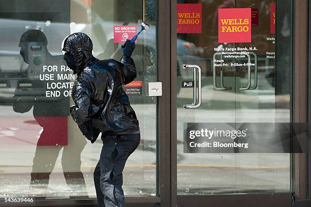 Protester breaks the glass door of a Wells Fargo & Co. Bank branch during an Occupy Seattle May Day rally and anti-capitalist march in Seattle,...