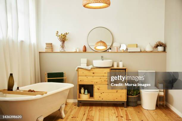 sink with toiletries kept on cabinet by bathtub - lavabo fotografías e imágenes de stock