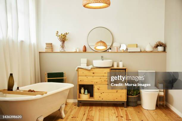 sink with toiletries kept on cabinet by bathtub - toilettes photos et images de collection