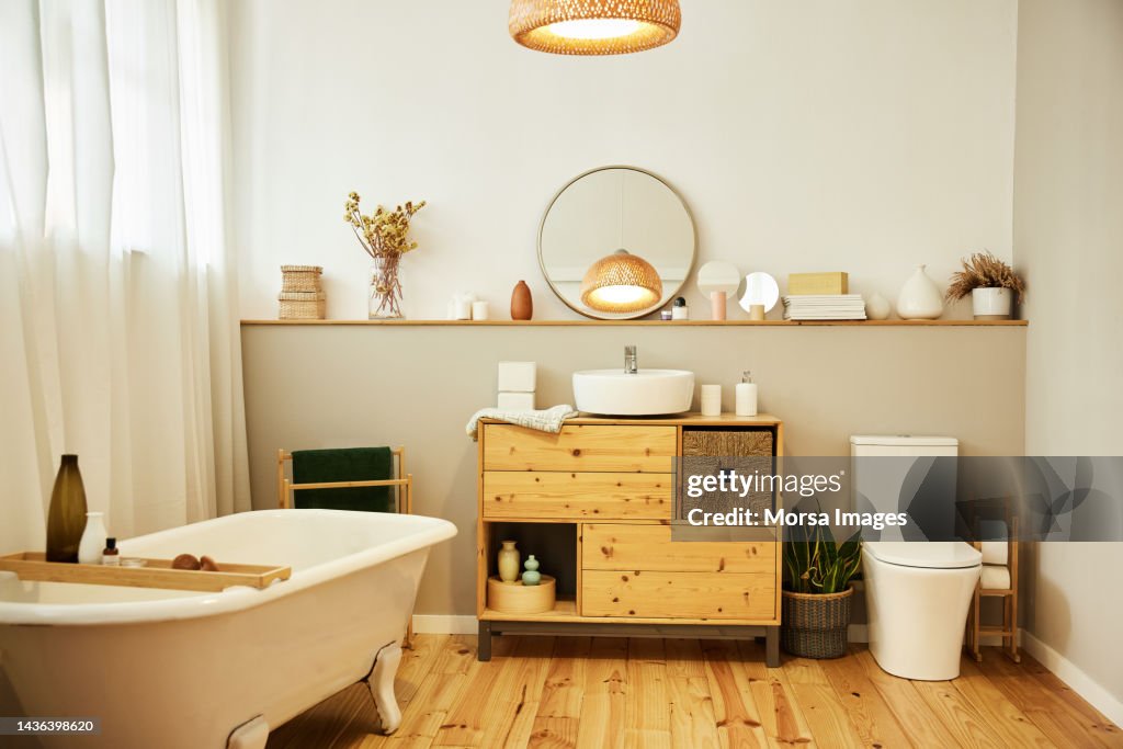 Sink with toiletries kept on cabinet by bathtub