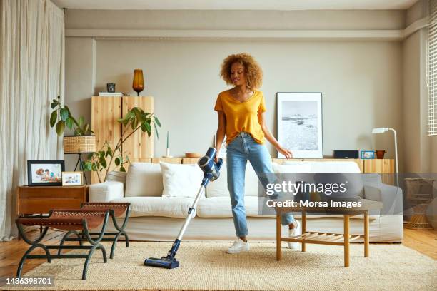 woman cleaning carpet with vacuum cleaner at home - home cleaning fotografías e imágenes de stock