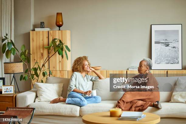 women talking with each other on sofa at home - mother daughter couch imagens e fotografias de stock