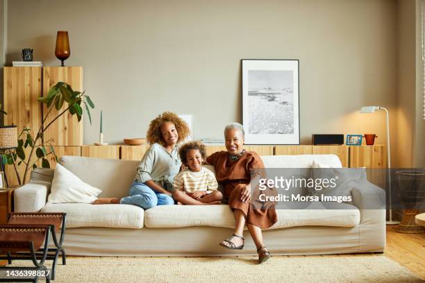 happy family sitting on sofa in living room - grandmas living room stockfoto's en -beelden