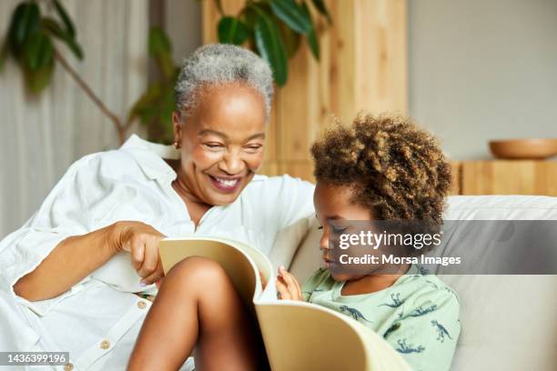 happy grandmother storytelling grandson at home - nietos fotografías e imágenes de stock