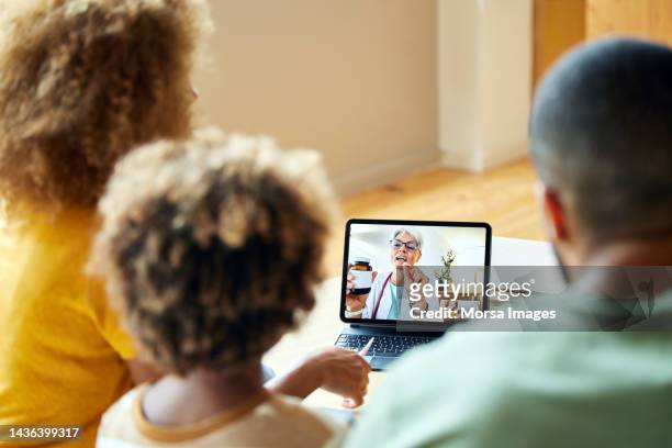 doctor advising family through video call at home - storytelling recomendation stock-fotos und bilder