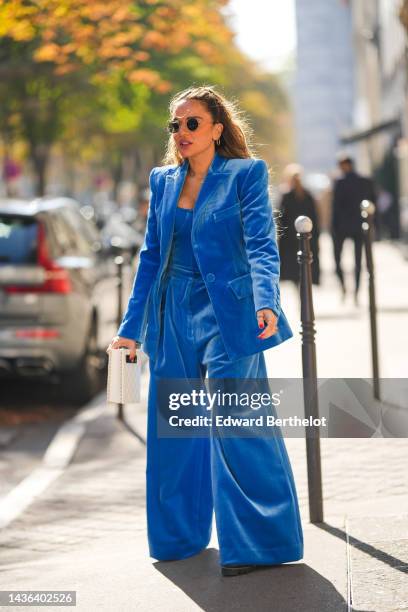 Guest wears black circle sunglasses, gold earrings, gold chain necklaces, a royal blue velvet blazer jacket, matching royal blue velvet wide legs...