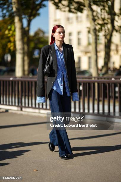 Guest wears a navy blue and white striped print pattern shirt, a black blazer jacket, a black shiny leather grained shoulder bag, navy blue denim...